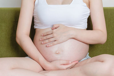 Midsection of woman sitting on bed