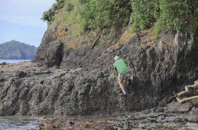 Rear view of man climbing on rock at beach