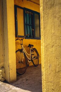 Bicycle parked against yellow window