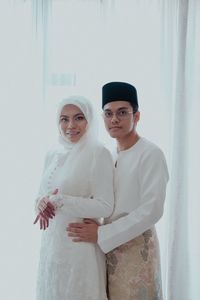 Portrait of couple standing by curtain