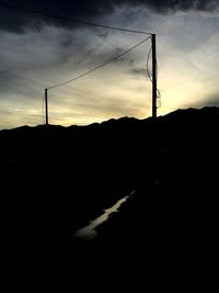 Silhouette of electricity pylon against sky at sunset