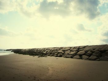 Scenic view of beach against cloudy sky