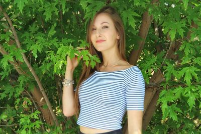 Portrait of smiling woman standing by tree