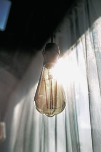 Low angle view of light bulb hanging on ceiling