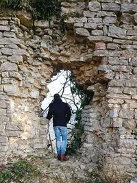 Rear view of man walking against brick wall