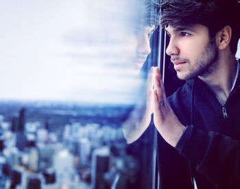 Portrait of young man looking away against buildings in city