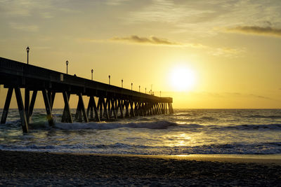 Pier over sea against sky during sunset