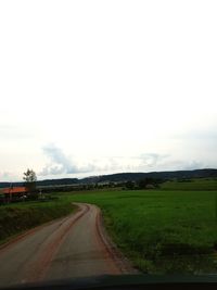 Road amidst field against sky