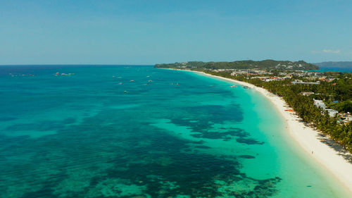 Tropical white beach with tourists and hotels near the blue sea, aerial view. 