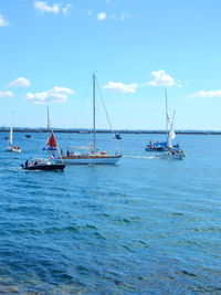 Boats sailing in sea against blue sky