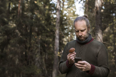 Man holding mushroom and cell phone