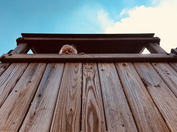 Low angle portrait of girl on wooden equipment at playground