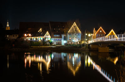 Illuminated bridge over river against sky at night