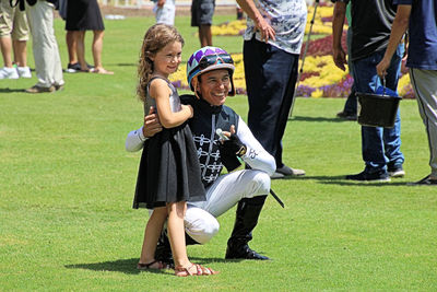 Full length of smiling father and daughter posing on field