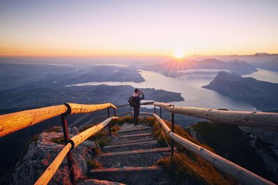 Man on staircase against sky during sunset