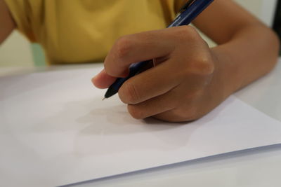 Midsection of man holding paper on table