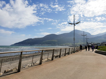 People on street by sea against sky