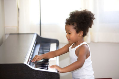 Side view of woman playing with piano at home