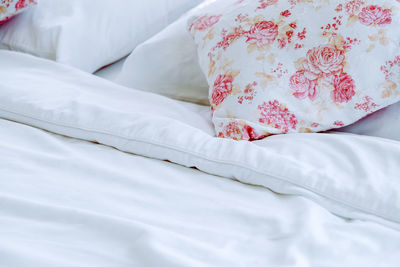 Bright bedroom interior with flower pattern pillows on bed 