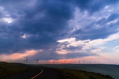 Road by landscape against sky during sunset