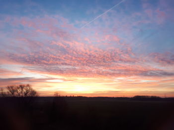 Silhouette landscape against dramatic sky during sunset