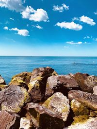 Rocks by sea against blue sky