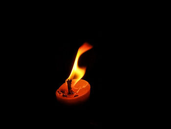 Close-up of lit candle against black background