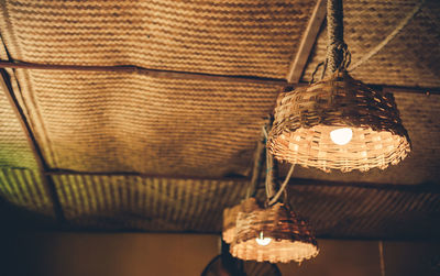 Low angle view of illuminated wicker pendant lights at cafe