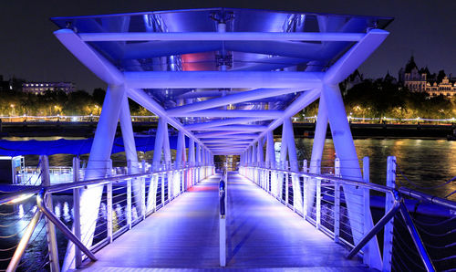 Illuminated london eye pier over thames river in city at night