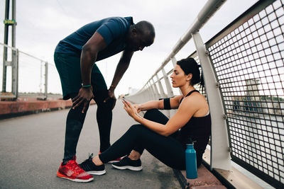 Female athlete showing mobile phone to sportsman on footbridge