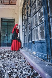 Woman standing by window of building