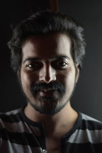 Portrait of young man standing against black background