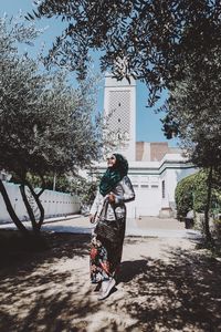 Full length of woman with umbrella against trees