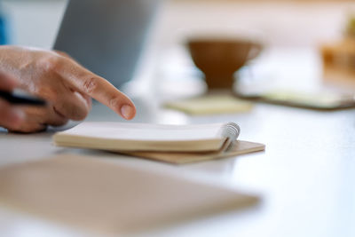 Close-up of hand pointing at book on table