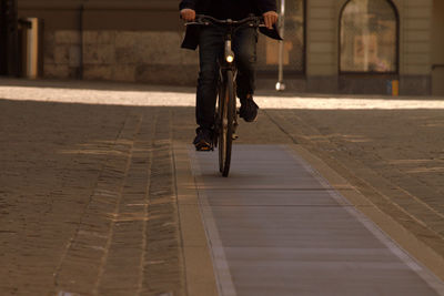 Low section of man riding bicycle on footpath