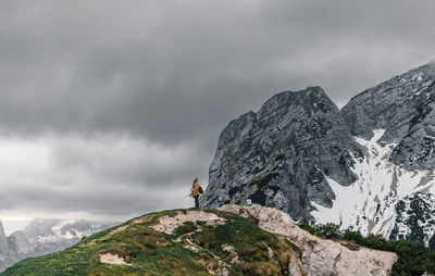 Woman standing on viewpoint in mountains under gray sky in winter