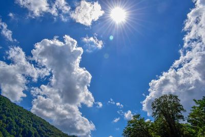 Low angle view of sunlight streaming through clouds
