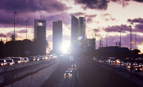 Panoramic view of city street and buildings against sky during sunset