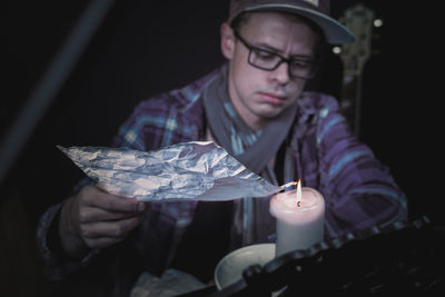 Close-up of young man burning foil on candle