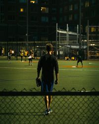 Rear view of men playing soccer on field