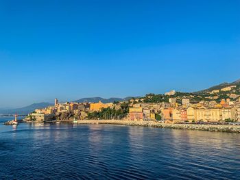 View of town by sea against blue sky