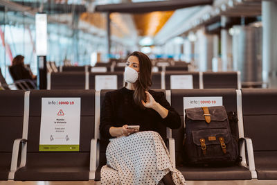 Woman wearing mask sitting at airport