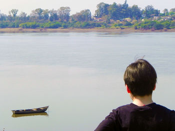 Rear view of man on boat against trees