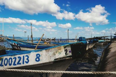 Boats moored at harbor against sky