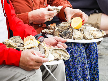 Midsection of man holding ice oyster on the knees, ready to eat