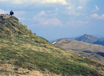 Rear view of hiker standing on mountain against sky