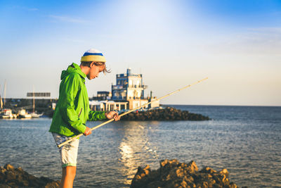 Side view of boy fishing at beach