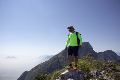 Man standing on rock against sky