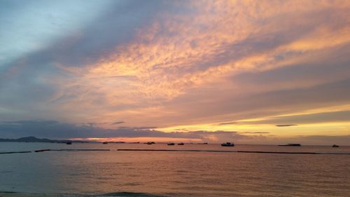 Scenic view of sea against cloudy sky at sunset