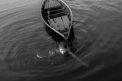 High angle view of boy swimming by boat in lake